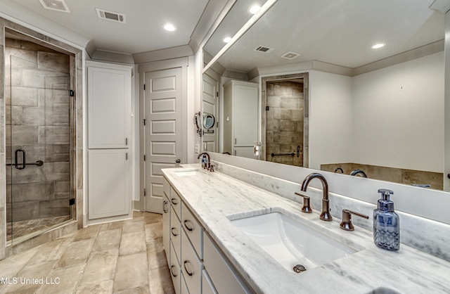 bathroom with a shower with shower door, vanity, and ornamental molding