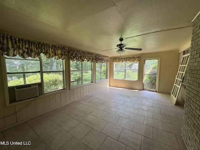 unfurnished sunroom with cooling unit, a textured ceiling, wooden walls, and tile patterned floors