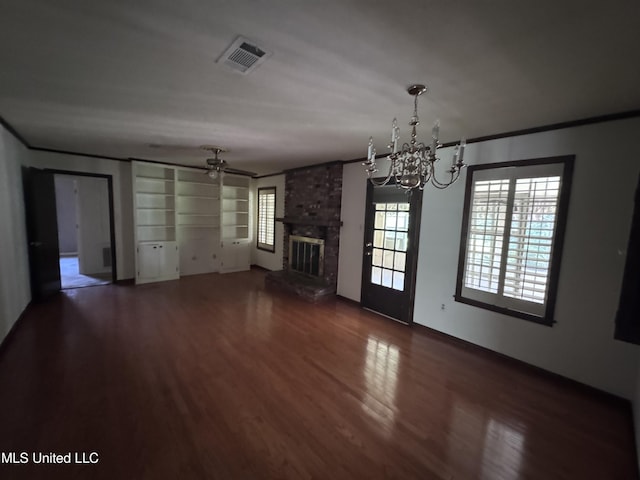 unfurnished dining area with a ceiling fan, wood finished floors, a chandelier, a fireplace, and ornamental molding