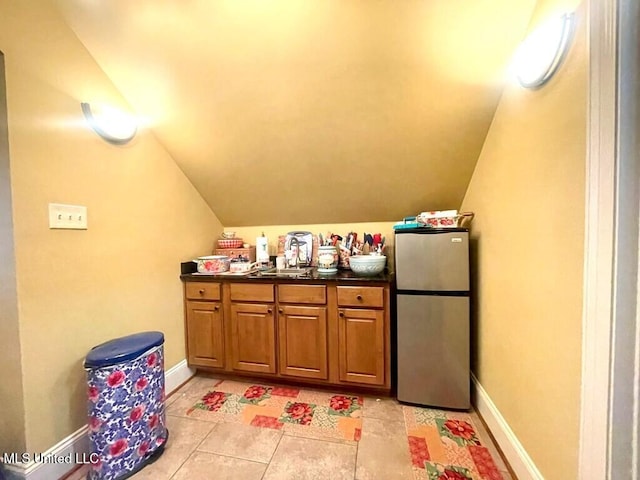 6 Lunker Ln, Poplarville, MS 39470 - bar area featuring freestanding refrigerator, vaulted ceiling, a sink, light tile patterned flooring, and baseboards