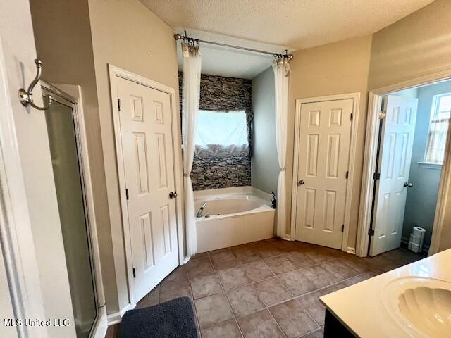 9064 Kyle Duran Ln, Olive Branch, MS 38654 - bathroom with a garden tub, vanity, a stall shower, tile patterned flooring, and a textured ceiling