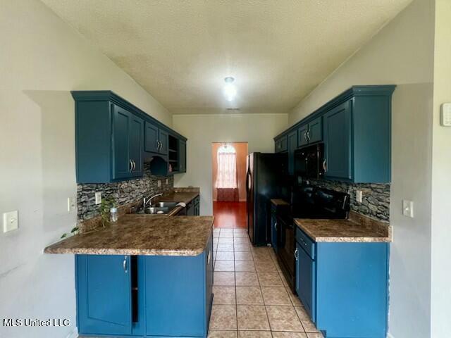 9064 Kyle Duran Ln, Olive Branch, MS 38654 - kitchen featuring black appliances, backsplash, a peninsula, blue cabinets, and light tile patterned flooring