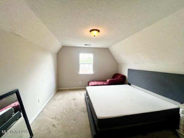 9064 Kyle Duran Ln, Olive Branch, MS 38654 - bedroom featuring light colored carpet, vaulted ceiling, and a textured ceiling