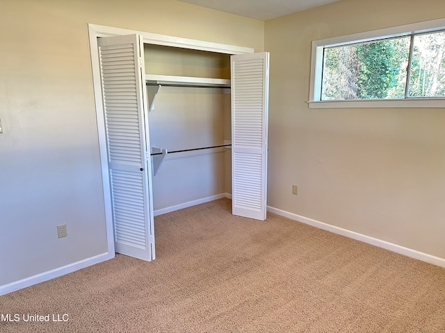 unfurnished bedroom with light carpet and a closet