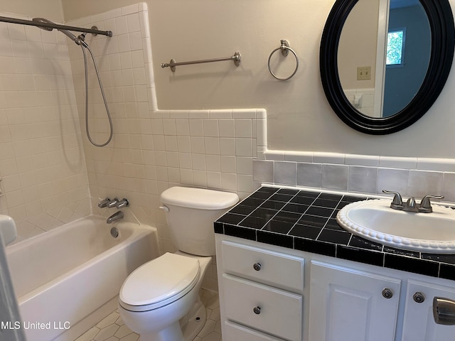 full bathroom with tiled shower / bath, tile walls, toilet, vanity, and tile patterned floors