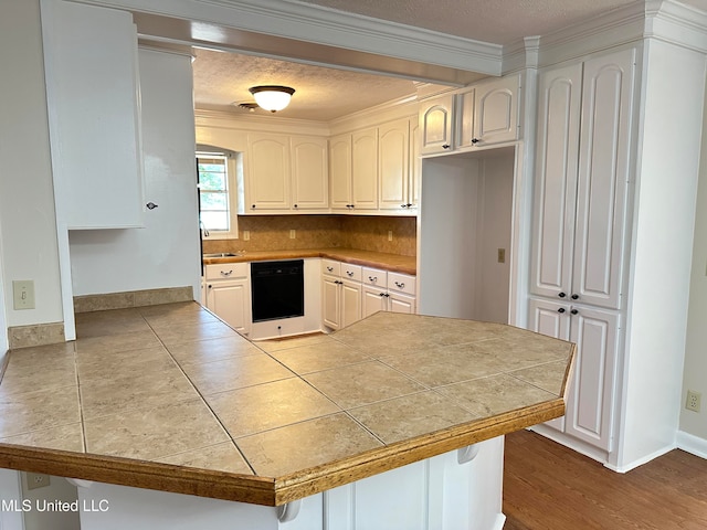 kitchen featuring a kitchen bar, dishwasher, white cabinets, and kitchen peninsula