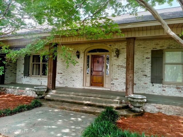 99 Duncan Rd, Inverness, MS 38753 - view of exterior entry with brick siding, roof with shingles, and a porch