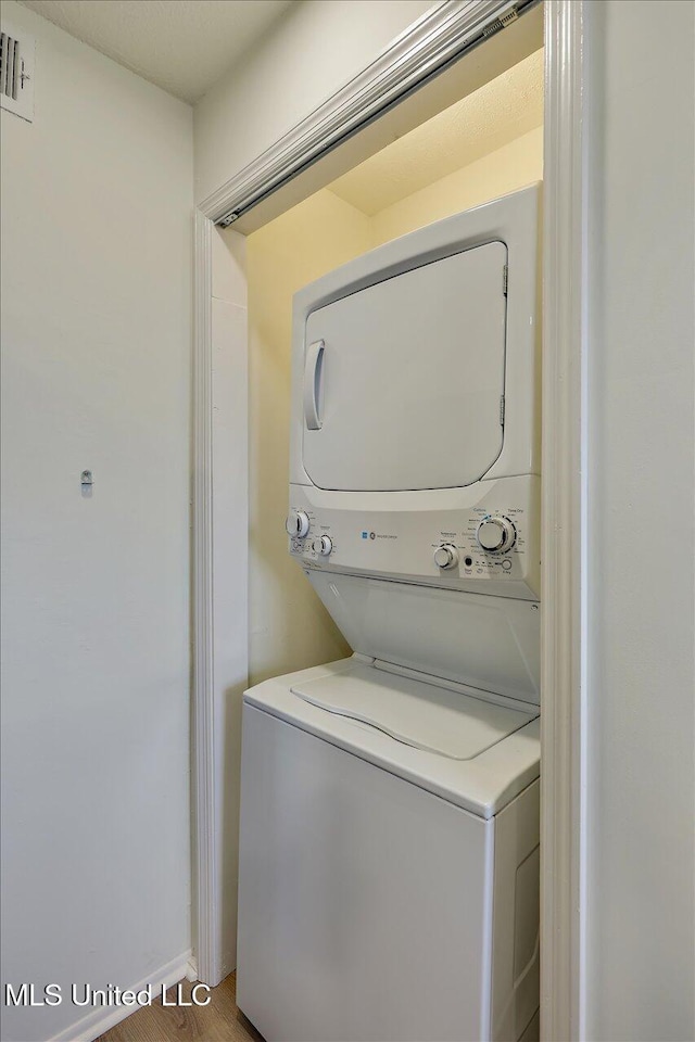 clothes washing area with stacked washer / drying machine, laundry area, and visible vents