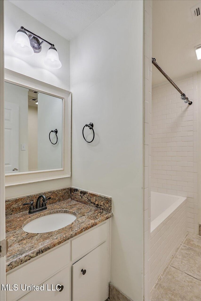 full bathroom featuring a textured ceiling, vanity, visible vents, and tile patterned floors