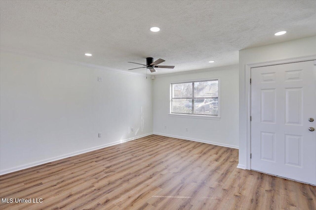 unfurnished room featuring light wood-style flooring, crown molding, baseboards, and a textured ceiling