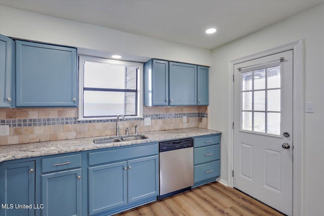 kitchen featuring tasteful backsplash, light wood-style floors, dishwasher, blue cabinetry, and a sink