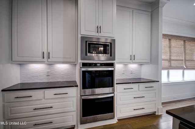 251 Westlake Cir, Madison, MS 39110 - kitchen with appliances with stainless steel finishes, dark countertops, dark wood finished floors, backsplash, and white cabinets