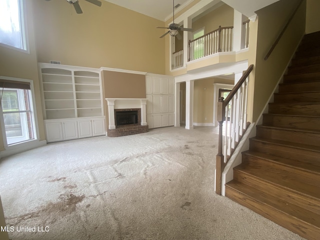 unfurnished living room with a fireplace, a high ceiling, and plenty of natural light