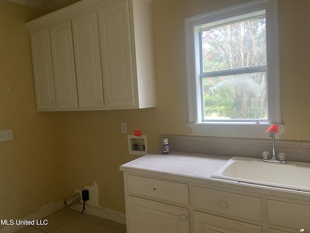 washroom featuring a wealth of natural light, hookup for a washing machine, light tile patterned floors, and cabinets