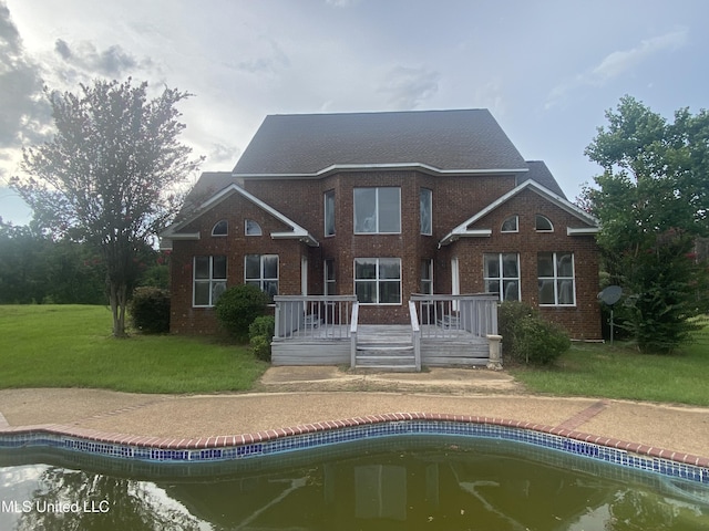 rear view of property featuring a lawn and a swimming pool side deck