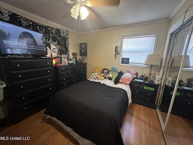 bedroom with ceiling fan, hardwood / wood-style flooring, ornamental molding, and a textured ceiling