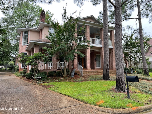 view of front facade with a front yard, a porch, and a balcony