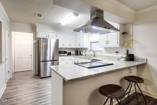 3109 Breezy Hill Ln, Ocean Springs, MS 39564 - kitchen with stainless steel appliances, island range hood, a peninsula, light wood-style flooring, and light stone countertops