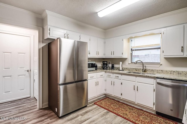 3109 Breezy Hill Ln, Ocean Springs, MS 39564 - kitchen featuring stainless steel appliances, a sink, light wood finished floors, crown molding, and white cabinets
