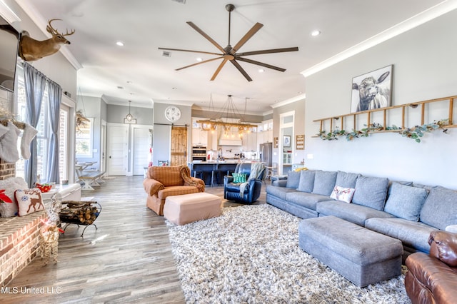 living room with ceiling fan with notable chandelier, light hardwood / wood-style flooring, and crown molding