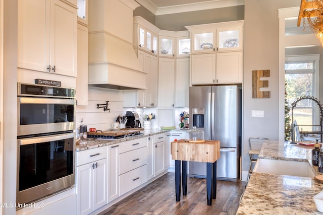 kitchen with light stone countertops, sink, stainless steel appliances, and custom exhaust hood