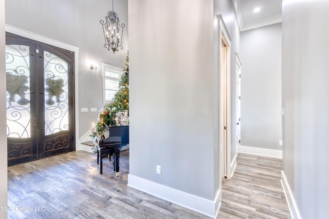 entryway featuring an inviting chandelier, ornamental molding, light hardwood / wood-style flooring, and french doors