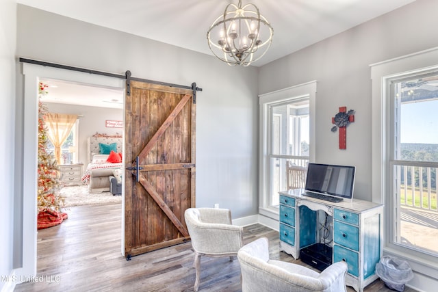 sitting room featuring a barn door, light hardwood / wood-style floors, and an inviting chandelier