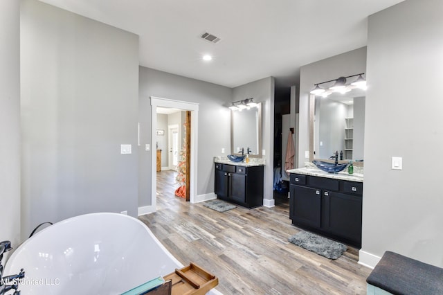 bathroom featuring a bath, vanity, and wood-type flooring