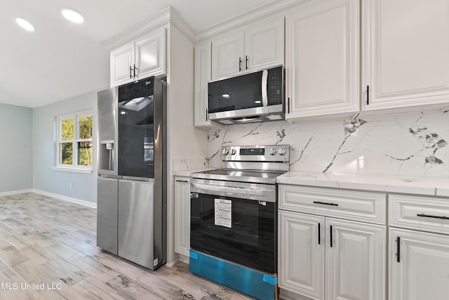 6071 Comanche St, Kiln, MS 39556 - kitchen with appliances with stainless steel finishes, baseboards, tasteful backsplash, white cabinets, and light wood finished floors