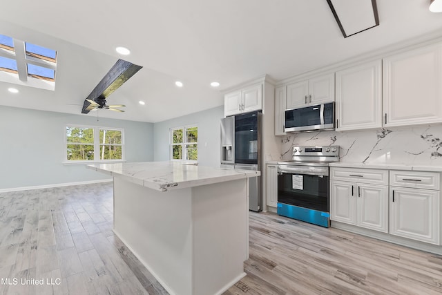 kitchen featuring stainless steel appliances, decorative backsplash, a kitchen island, white cabinetry, and light wood-type flooring