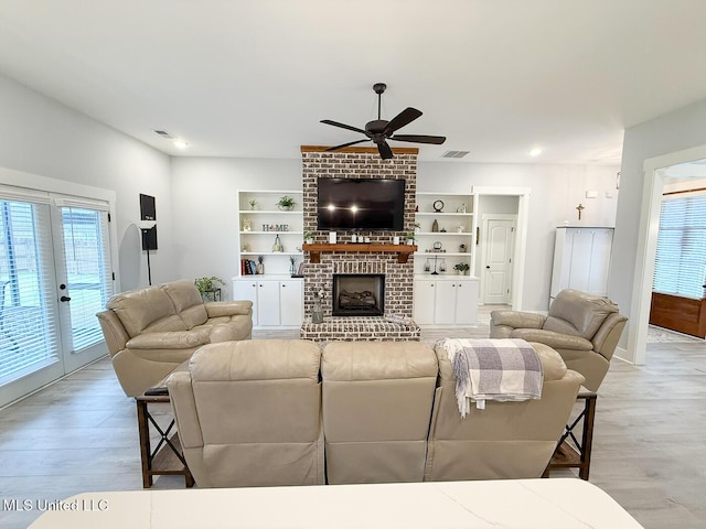 2290 Loisy Blvd, Hernando, MS 38632 - living room featuring a brick fireplace, a ceiling fan, light wood-style floors, and french doors