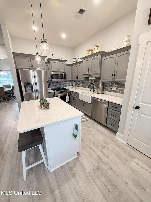 2290 Loisy Blvd, Hernando, MS 38632 - kitchen featuring stainless steel appliances, gray cabinets, a sink, light wood-style floors, and a center island