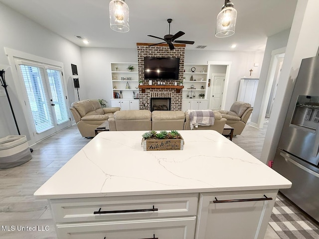 2290 Loisy Blvd, Hernando, MS 38632 - kitchen featuring stainless steel fridge, open floor plan, a ceiling fan, a brick fireplace, and white cabinets