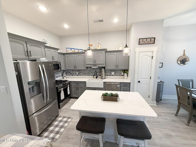2290 Loisy Blvd, Hernando, MS 38632 - kitchen with appliances with stainless steel finishes, a sink, gray cabinetry, decorative backsplash, and light wood finished floors