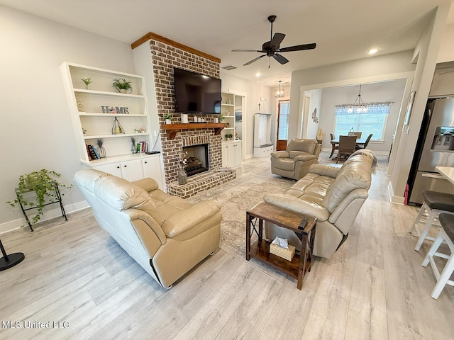 2290 Loisy Blvd, Hernando, MS 38632 - living area featuring light wood-style floors, ceiling fan, a fireplace, baseboards, and a chandelier