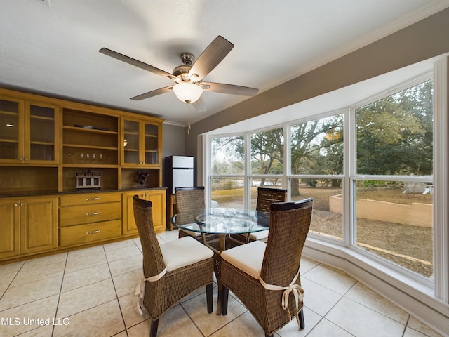 tiled dining area with crown molding and ceiling fan