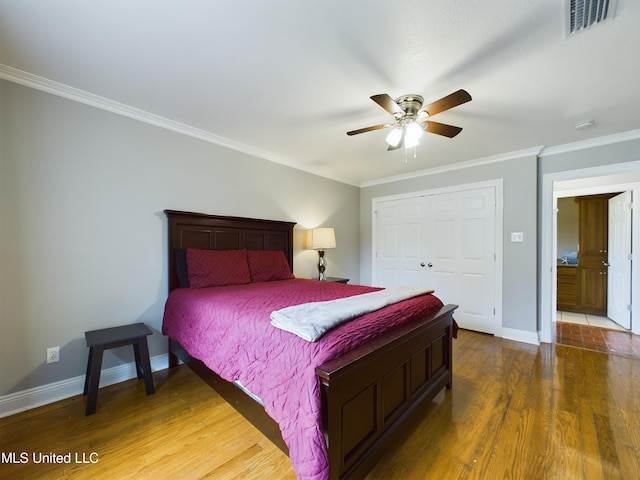 bedroom featuring ornamental molding, dark wood-type flooring, ceiling fan, and a closet