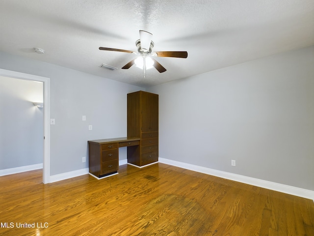 interior space with ceiling fan, wood-type flooring, and a textured ceiling