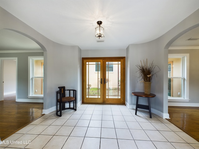 entryway featuring french doors, crown molding, and light wood-type flooring