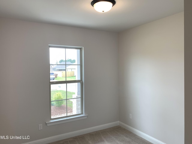 spare room with baseboards, light colored carpet, and a healthy amount of sunlight