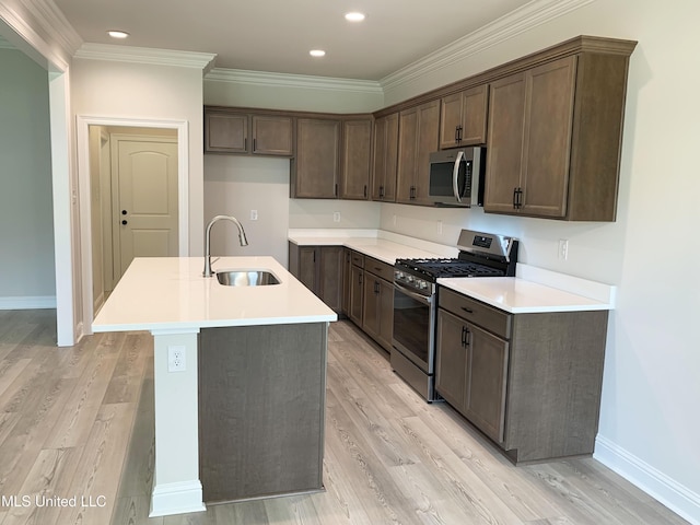 kitchen featuring a center island with sink, appliances with stainless steel finishes, light wood finished floors, and a sink