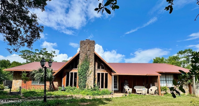 5114 Bay St, Pascagoula, MS 39567 - back of house with metal roof, a chimney, and a lawn