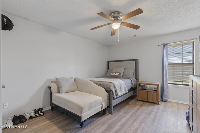 bedroom featuring a textured ceiling, ceiling fan, and light wood-type flooring