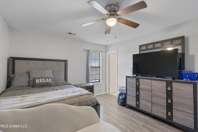 bedroom featuring a textured ceiling, ceiling fan, and light hardwood / wood-style floors