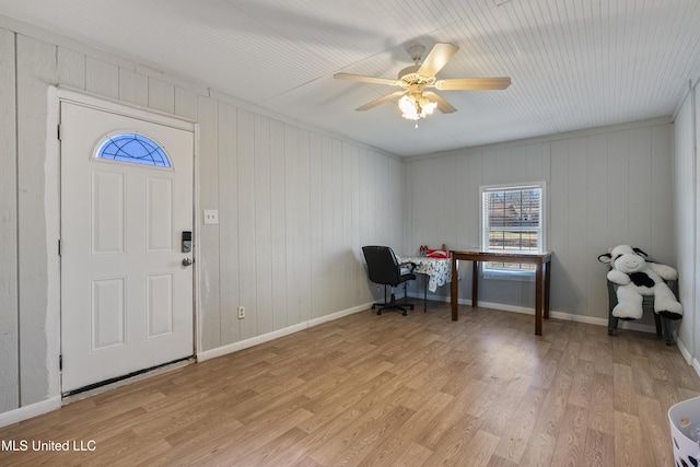 office area with ceiling fan, wooden walls, and light hardwood / wood-style floors