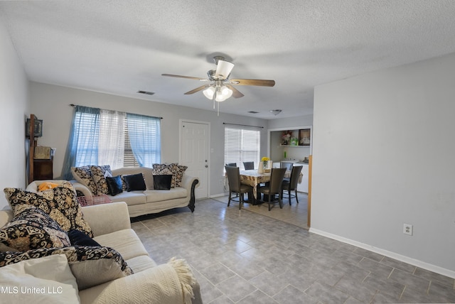 living room with ceiling fan and a textured ceiling