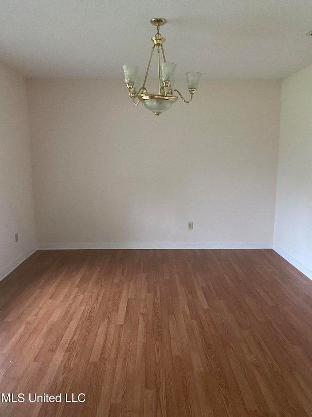 empty room featuring a notable chandelier and hardwood / wood-style flooring