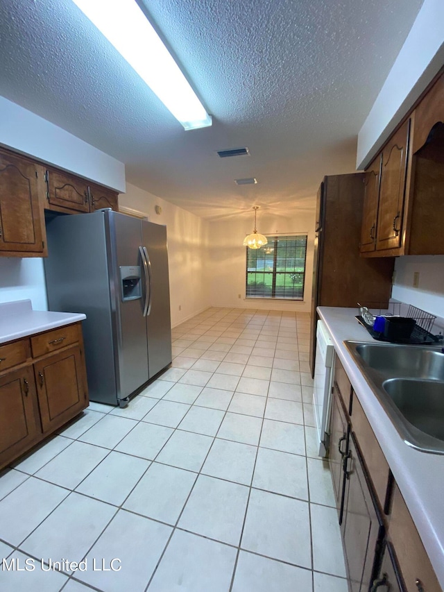 kitchen with stainless steel refrigerator with ice dispenser, sink, and a textured ceiling