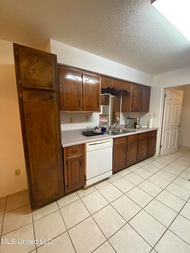 kitchen featuring dishwasher, a textured ceiling, sink, and light tile patterned floors