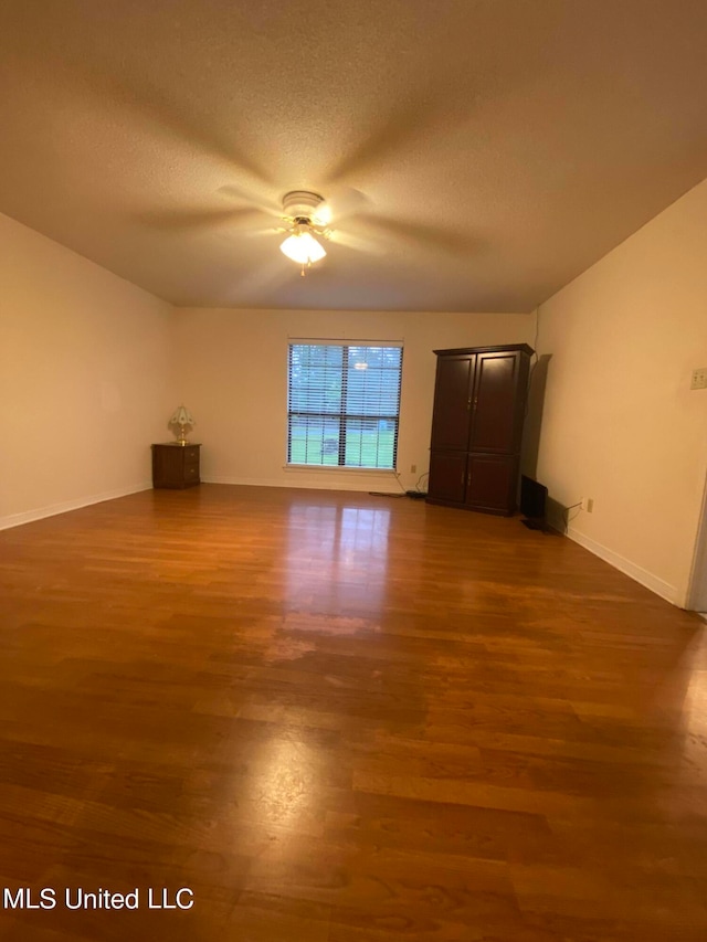 unfurnished room featuring ceiling fan, a textured ceiling, and dark hardwood / wood-style flooring